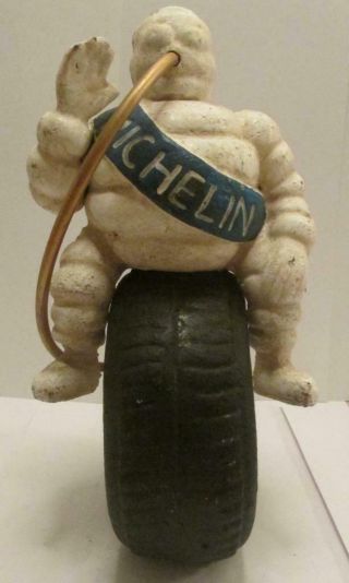 Michelin Man Sitting On A Tire With Hose Blowing Up The Tire