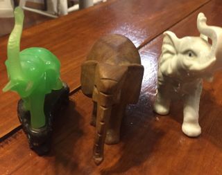 Three SMALL ELEPHANTS FIGURINES.  Wood,  Porcelain,  And Green Jade On Base 7