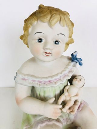 Large Bisque Porcelain Piano Baby Girl Holding Doll 11” Tall