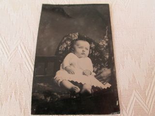 Vintage Tin Type Photogrpah Of Baby Sitting On Chair With Hand Supporting Baby